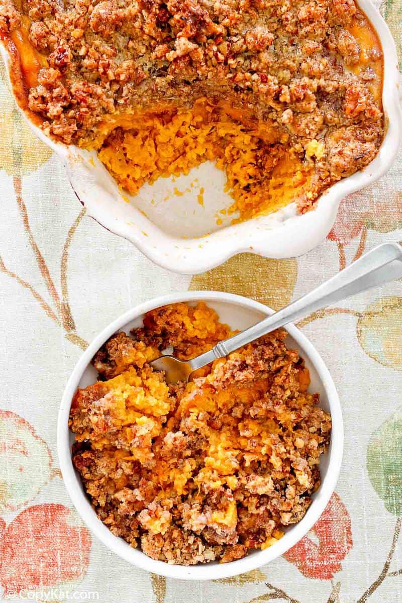 overhead view of sweet potato casserole with pecan topping in a bowl and baking dish