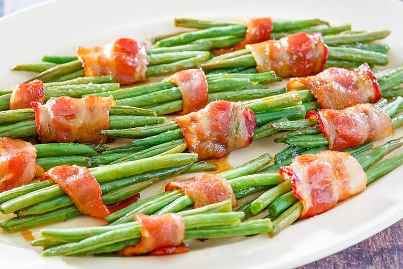bacon wrapped green bean bundles drizzled with brown sugar soy sauce on a platter