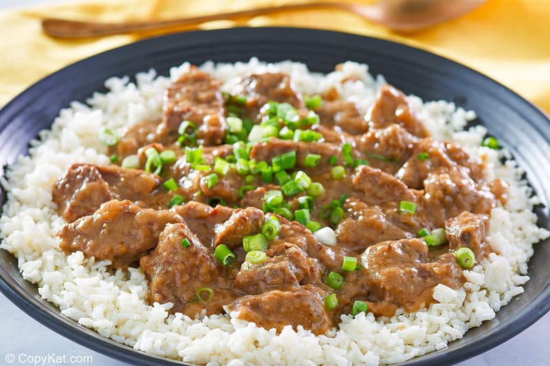 beef tips and gravy on top of rice on a black plate