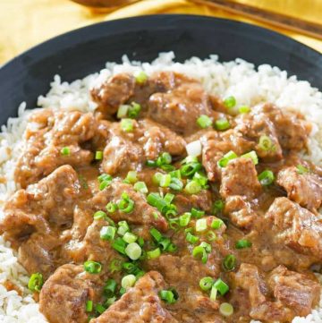 beef tips and gravy over rice on a black plate