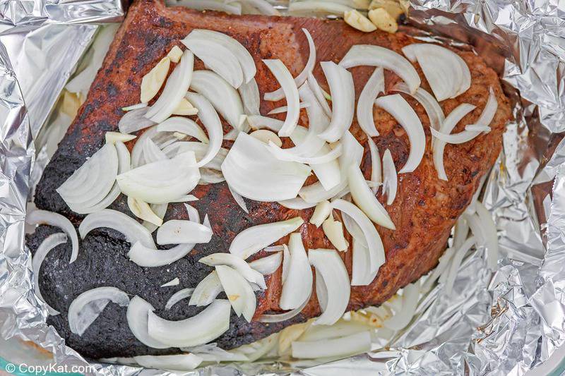 grilled dry rubbed brisket, onion slices, and garlic, in foil
