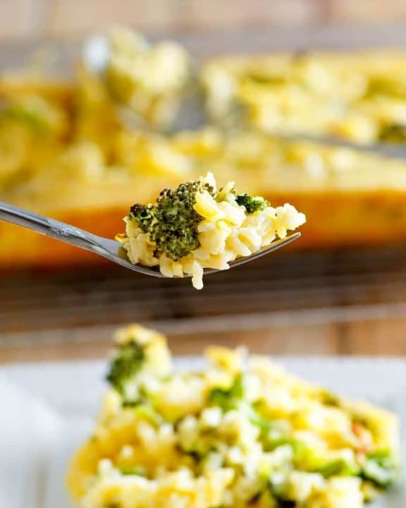 broccoli cheese rice casserole on a fork above a plate of it