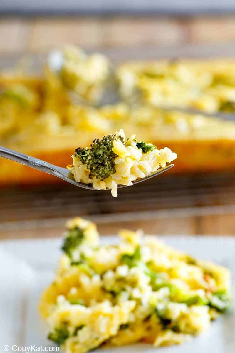 broccoli cheese rice casserole on a fork above a plate of it