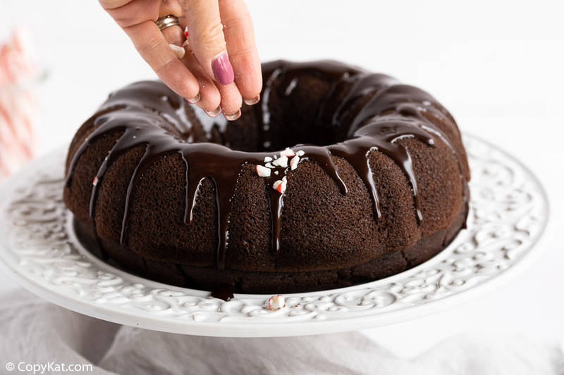 sprinkling crushed peppermint candy on top of a chocolate bundt cake