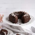 chocolate peppermint bundt cake slices on plates in front of the cake on a stand