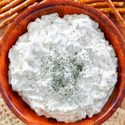 a bowl of dill pickle dip, pretzel sticks, and crackers