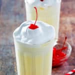 two eggnog milkshakes with whipped cream and a cherry on top