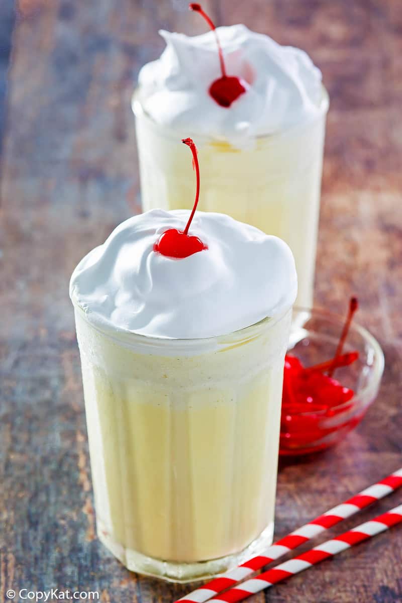 two eggnog milkshakes with whipped cream and a cherry on top