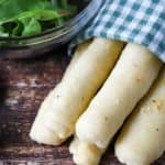 Homemade Olive Garden breadsticks wrapped in a kitchen towel and a salad