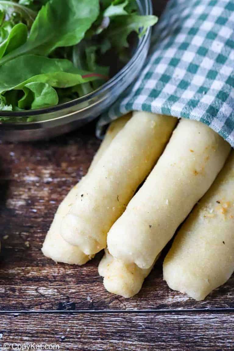Homemade Olive Garden breadsticks wrapped in a kitchen towel and a salad