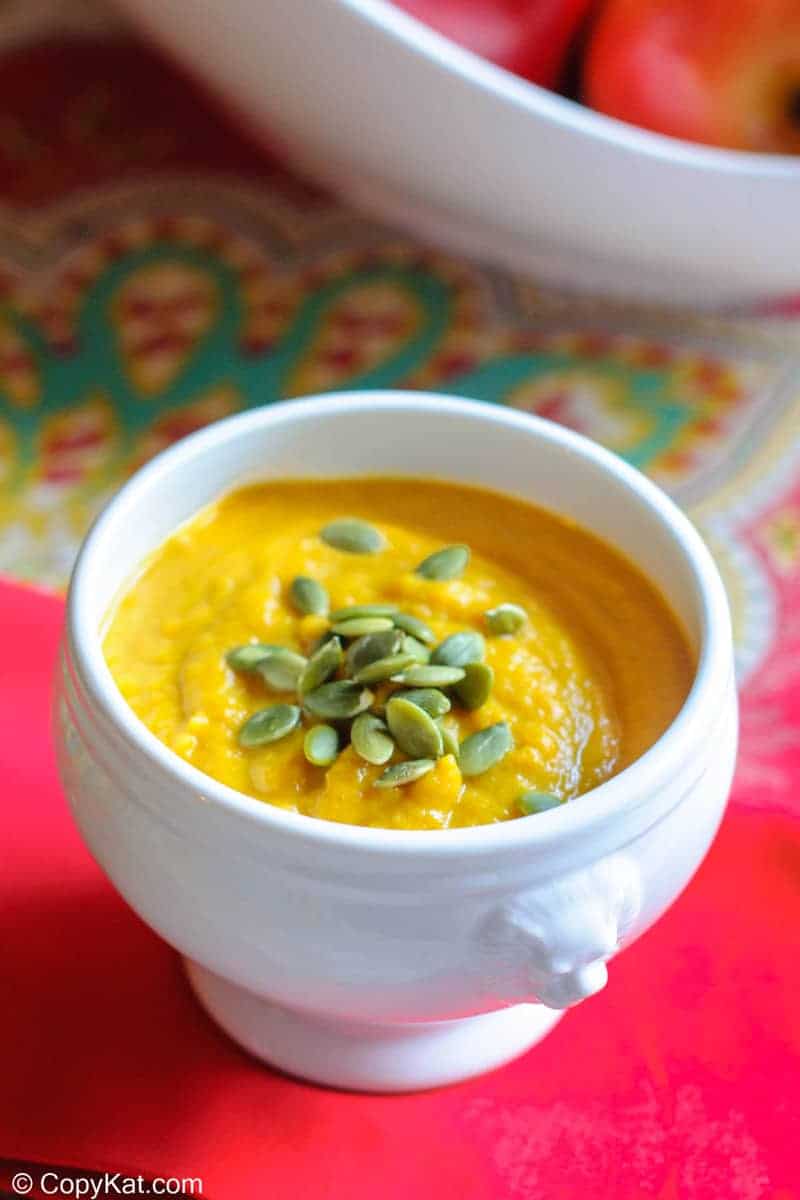 Homemade Panera autumn squash soup topped with pumpkin seed kernels