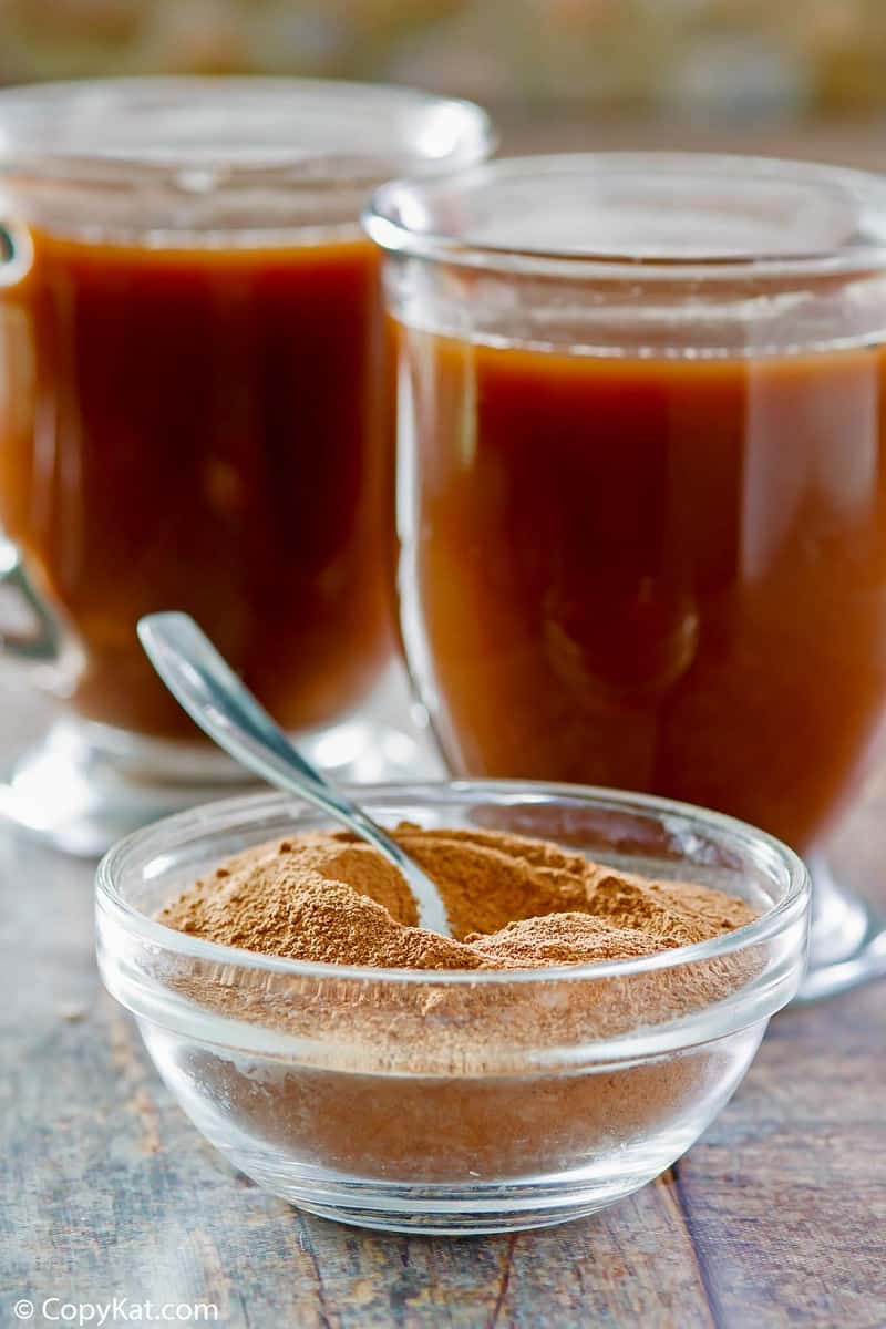 a bowl of homemade hot cocoa mix and two mugs of hot cocoa