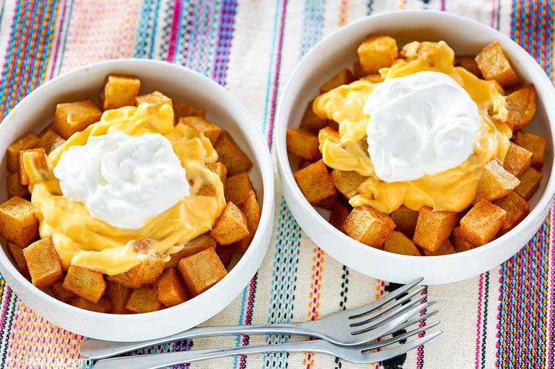 bowls of homemade Taco Bell Fiesta potatoes topped with nacho cheese and sour cream