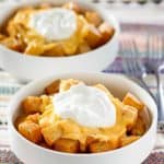 two bowls of fiesta potatoes topped with nacho sauce and sour cream