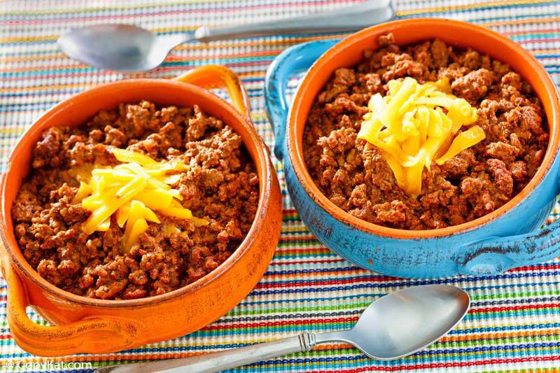 bowls of homemade Wick Fowler 2 Alarm Chili with shredded cheese on top