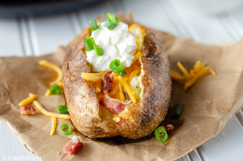 air fryer baked potato topped with butter, cheese, bacon, sour cream, and chives