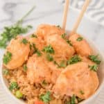 air fryer bang bang shrimp and sauce over rice in a bowl