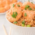 closeup photo of air fryer bang bang shrimp with sauce and rice in a bowl
