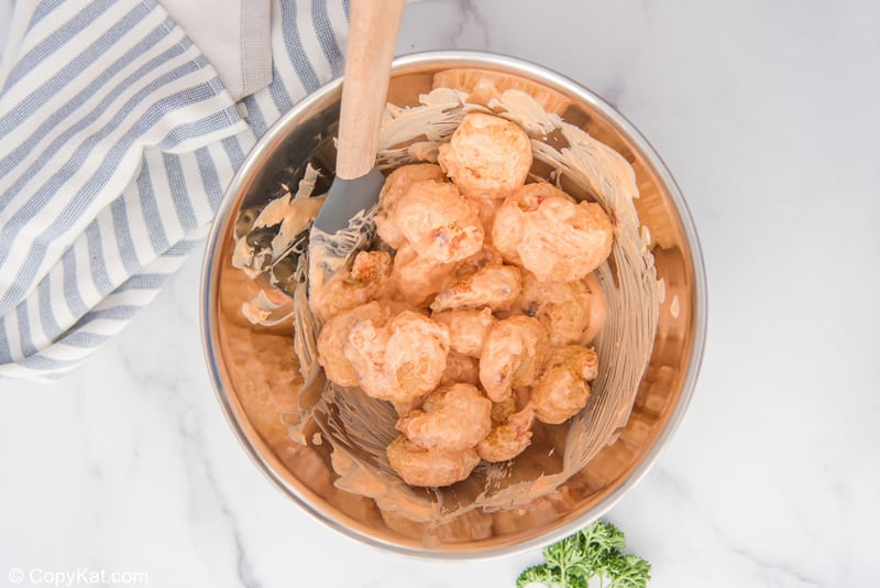 crispy breaded shrimp tossed with creamy chili sauce in a mixing bowl