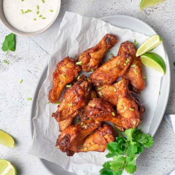 air fryer sweet and spicy chicken wings, lime wedges, and bowls of sauce and dressing