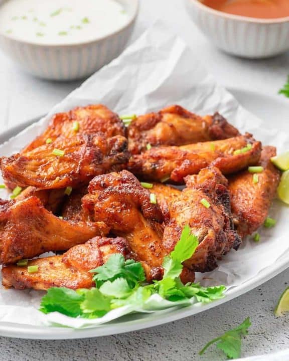 air fryer sweet and spicy chicken wings on a platter in front of bowls of dressing and sauce