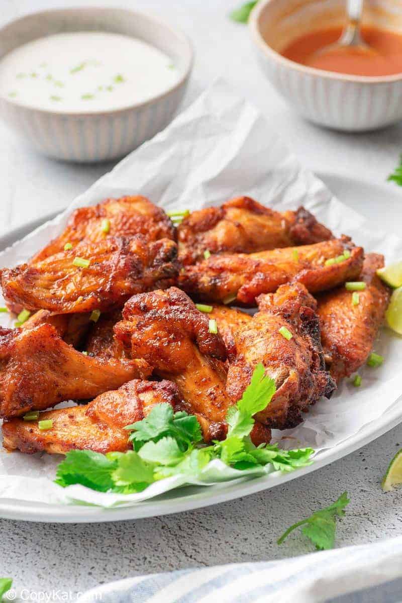 air fryer sweet and spicy chicken wings on a platter in front of bowls of dressing and sauce