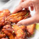 a hand holding an air fryer sweet and spicy chicken wing