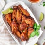 overhead view of air fryer sweet and spicy chicken wings in a dish and bowls of sauce and dressing