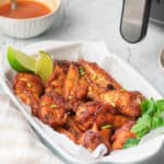 air fryer sweet and spicy chicken wings in a serving dish and a bowl of wing sauce