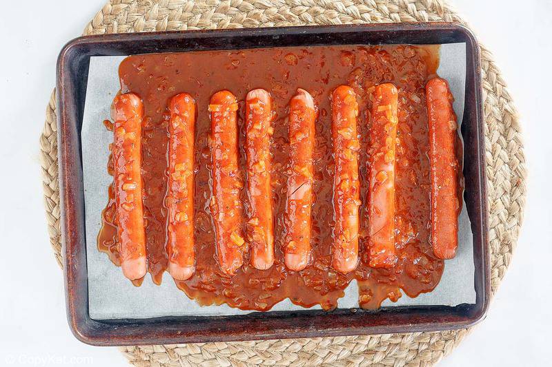 hot dogs and barbecue sauce on a baking sheet