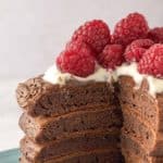 stack of chocolate pancakes with raspberries and whipped cream with slice cut out