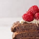 closeup photo of chocolate pancakes topped with whipped cream and raspberries