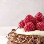 closeup of the top of a stack of chocolate pancakes with whipped cream and raspberries