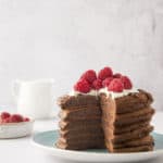 a stack chocolate pancakes with a wedge cut out on a plate