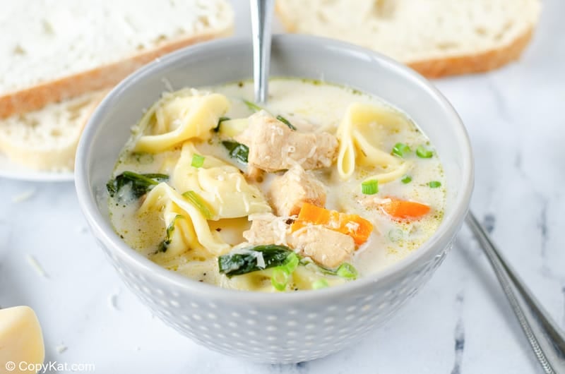 a bowl of creamy chicken tortellini soup and slices of bread