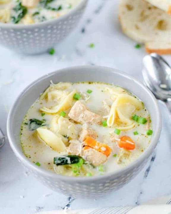 two bowls of creamy chicken tortellini soup and bread slices