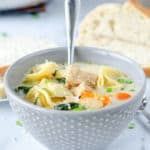 a bowl of creamy chicken tortellini soup and bread