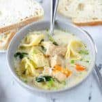 creamy chicken tortellini soup in a bowl and bread slices