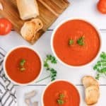 overhead view of three bowls of tomato soup, bread, and an Instant Pot