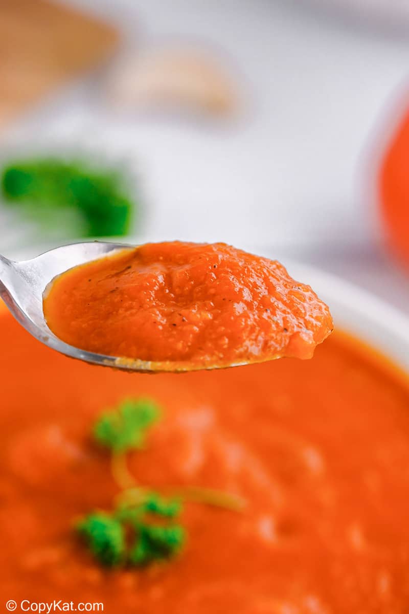 tomato soup on a spoon over a bowl of the soup