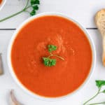 overhead view of Instant Pot tomato soup, garlic clove, and fresh parsley
