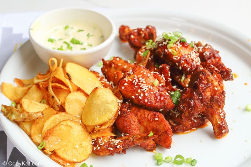 spicy chicken wings, potato chips, and dipping sauce on a plate