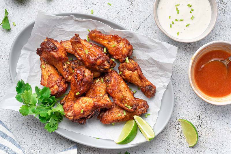 air fryer sweet and spicy chicken wings on a platter, wing sauce and dressing in bowls