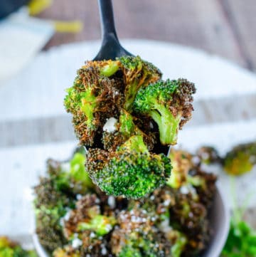 air fryer broccoli on a spoon over a bowl of air fried broccoli