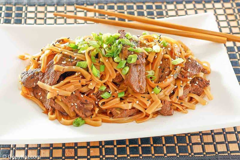 beef chow fun and chopsticks on a serving platter