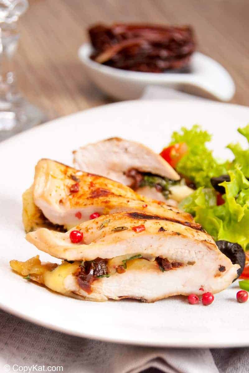 blue cheese and black olive stuffed chicken breast on a plate with a salad