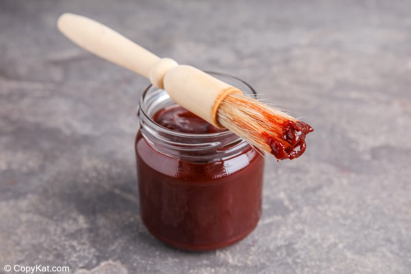 homemade bourbon BBQ sauce in a jar with a basting brush on top