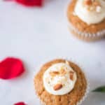 two carrot cake cupcakes and a rose