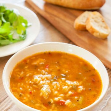 a bowl of chicken gumbo soup and bread on a cutting board