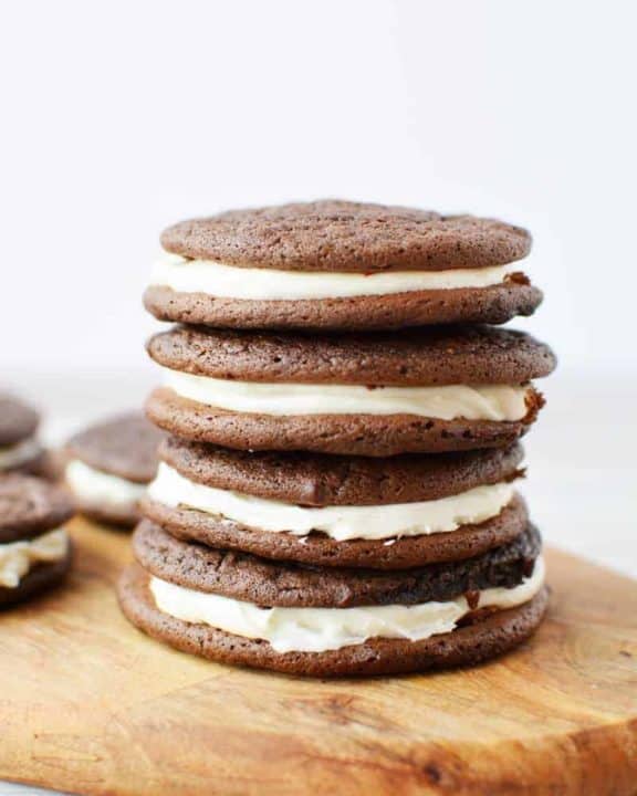 four chocolate sandwich cookies stacked on a wood board